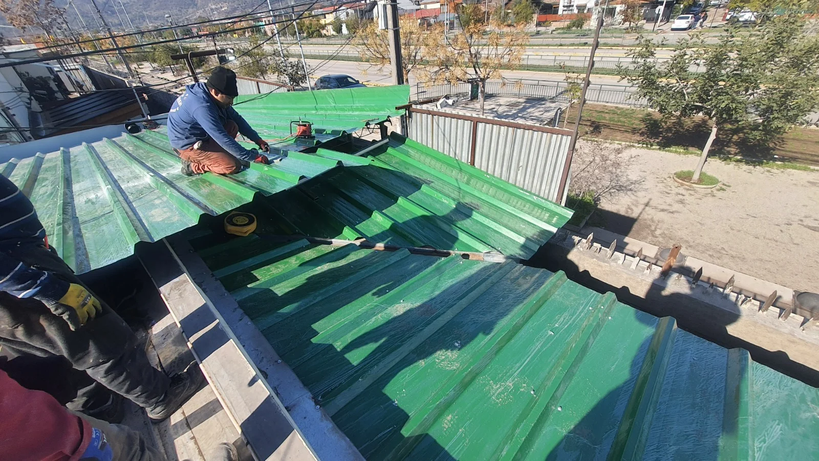 nstaladores trabajando en la colocación de planchas de zinc-alum acanaladas de color verde en la techumbre del Colegio Dorsal.